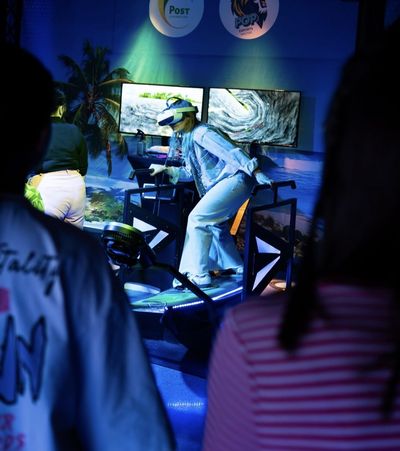 Animateur accompagnant un participant sur le simulateur de surf VR lors d'un événement